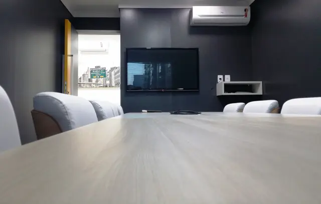 Mesa da sala de reunião de 10 lugares com a TV ao fundo