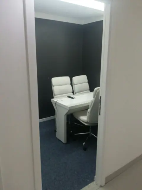 Sala privativa com porta, mesa e cadeiras brancas